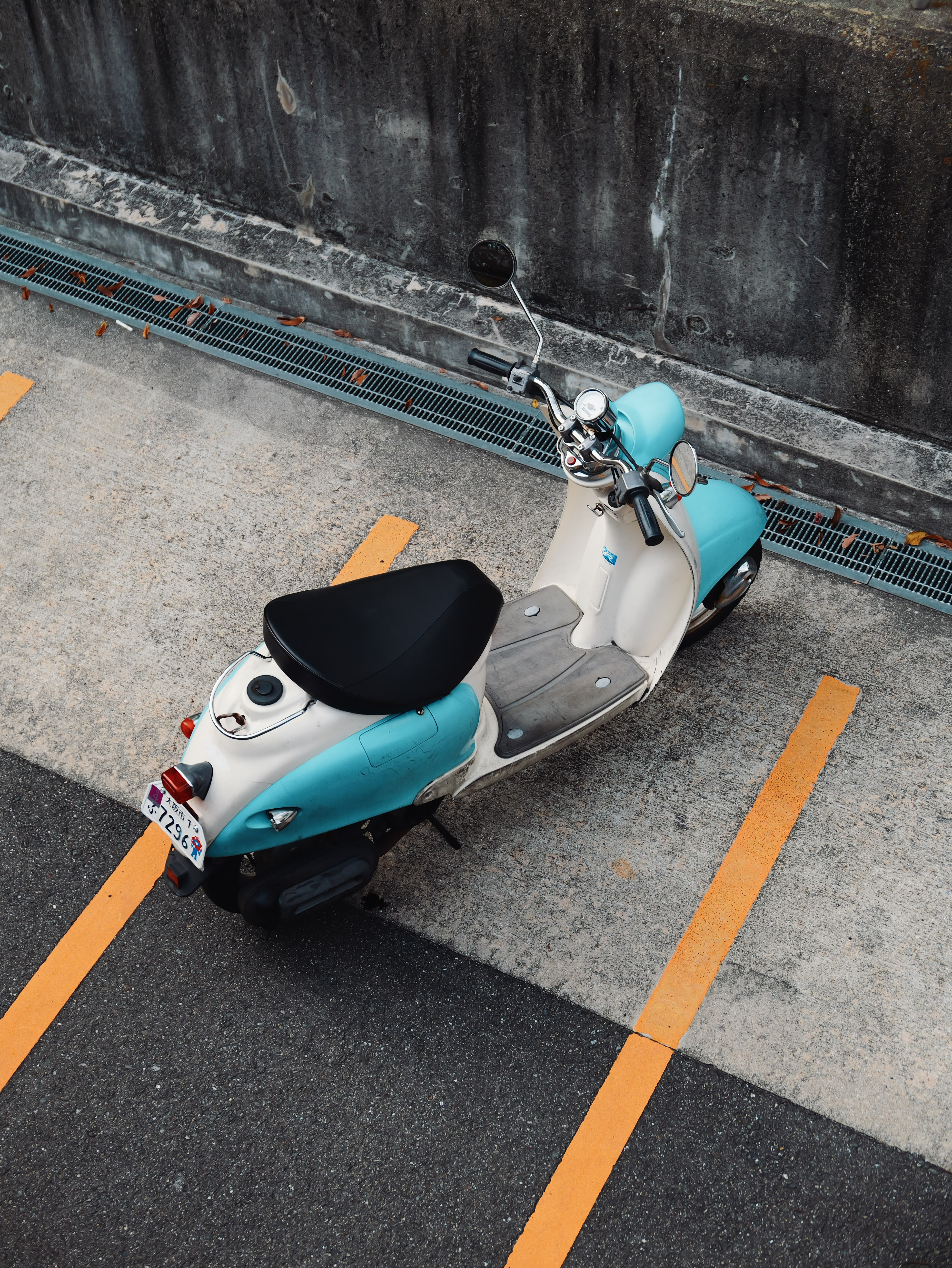 Blue and white scooter parked beside a concrete wall.