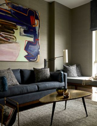Living room with muted dark green grasscloth wallpaper, oversized multicolor canvas art, dark sofa and wooden coffee table
