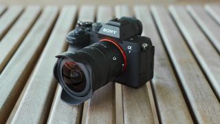 Sony Alpha mirrorless camera with the FE 8-14mm F3.5 G ultra-wide zoom lens resting on a wooden table.