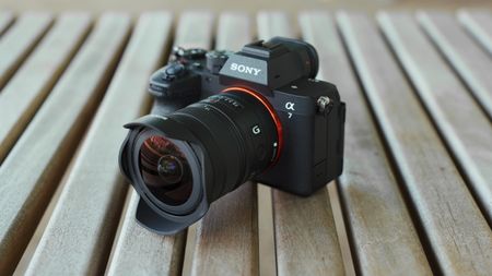 Sony Alpha mirrorless camera with the FE 8-14mm F3.5 G ultra-wide zoom lens resting on a wooden table.