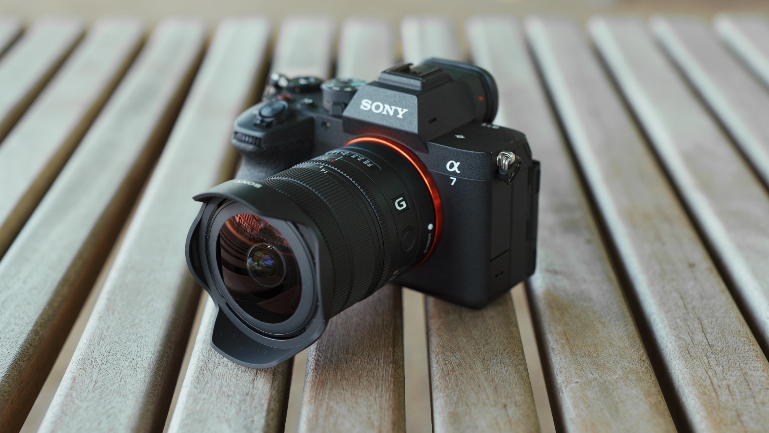 Sony Alpha mirrorless camera with the FE 8-14mm F3.5 G ultra-wide zoom lens resting on a wooden table.