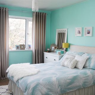 turquoise bedroom with bed and white table