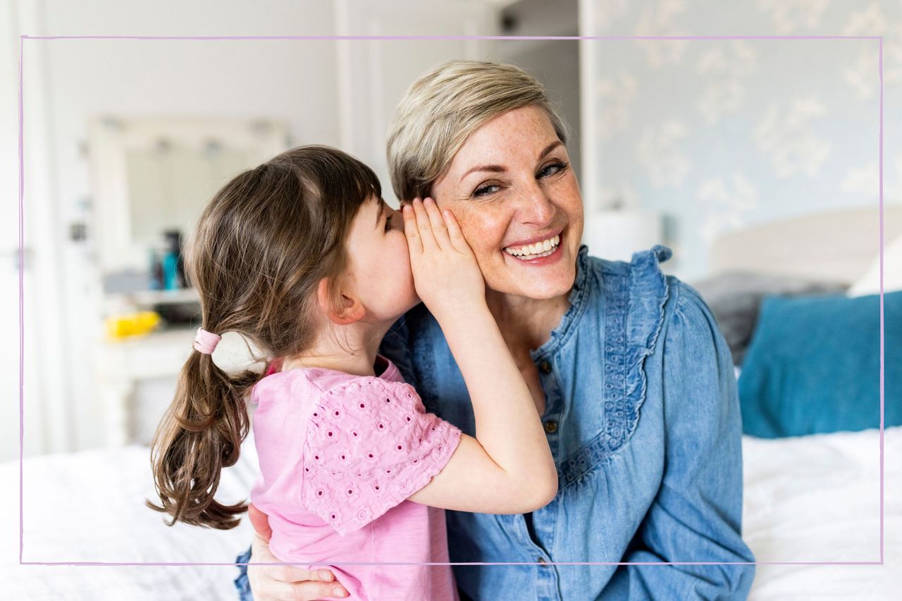 A little girl whispering into her mother&#039;s ear