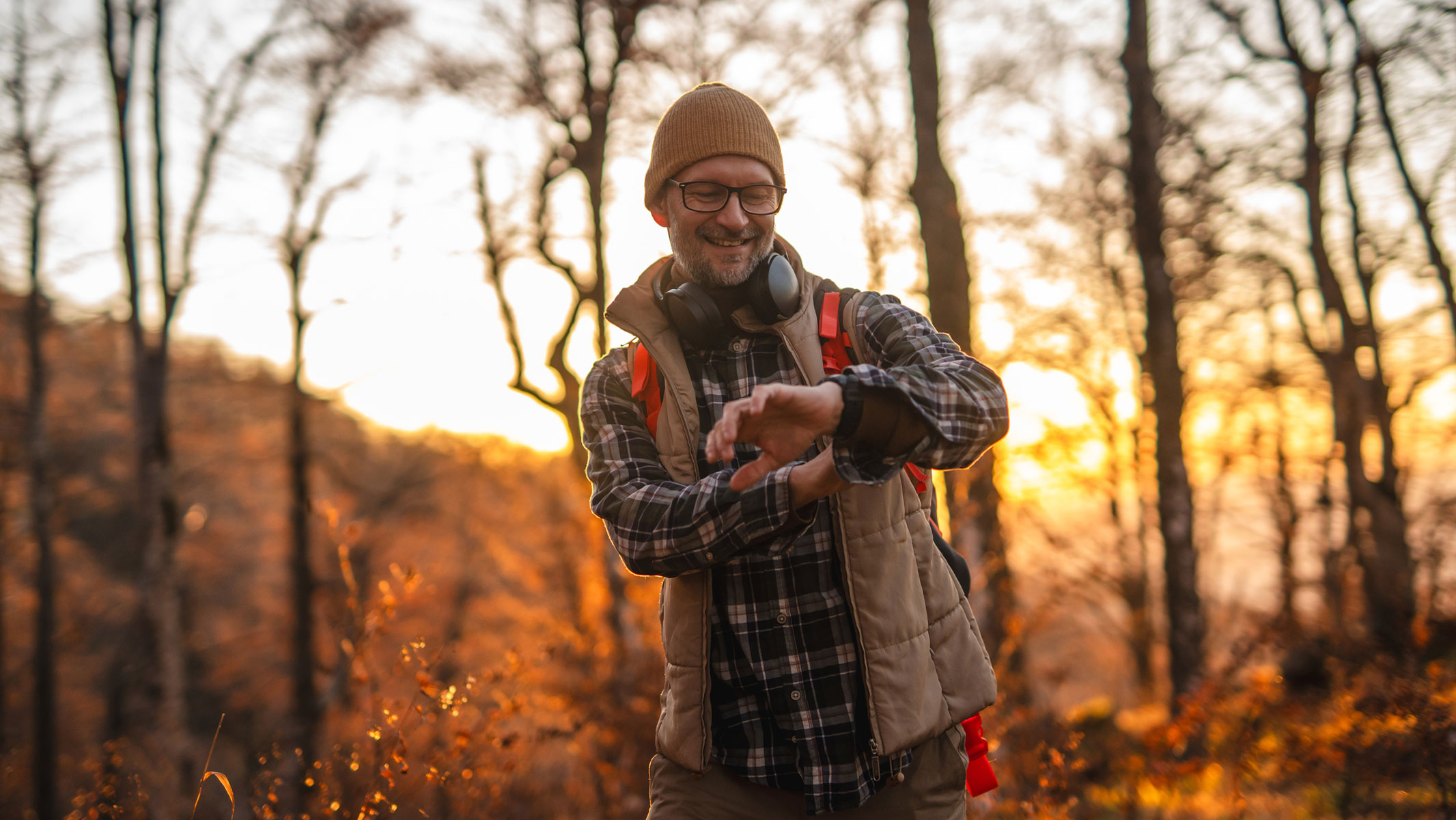 A picture of a man checking his smartwatch while on a hike