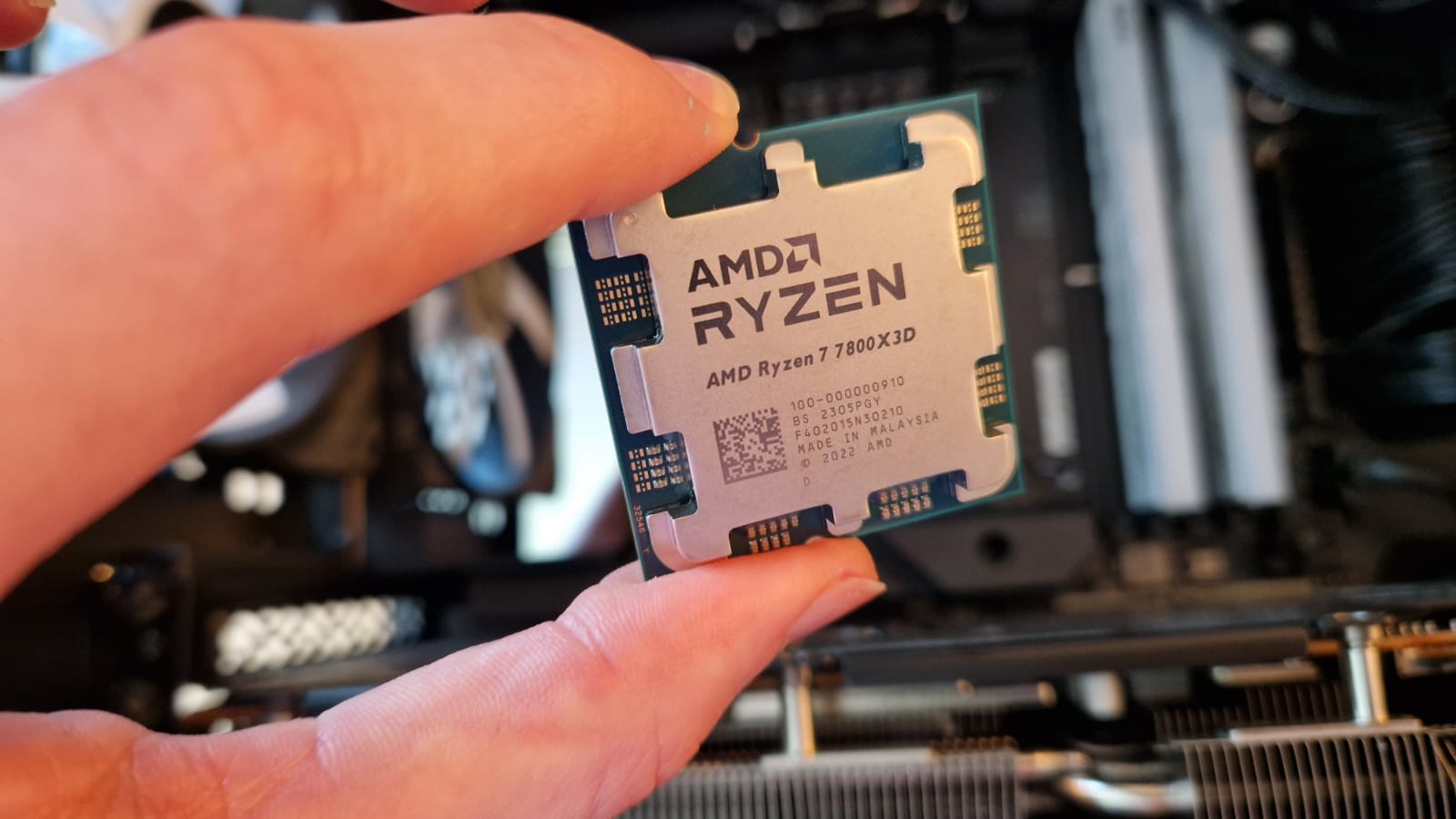 The AMD Ryzen 7 7800X3D processor being held by a reviewer