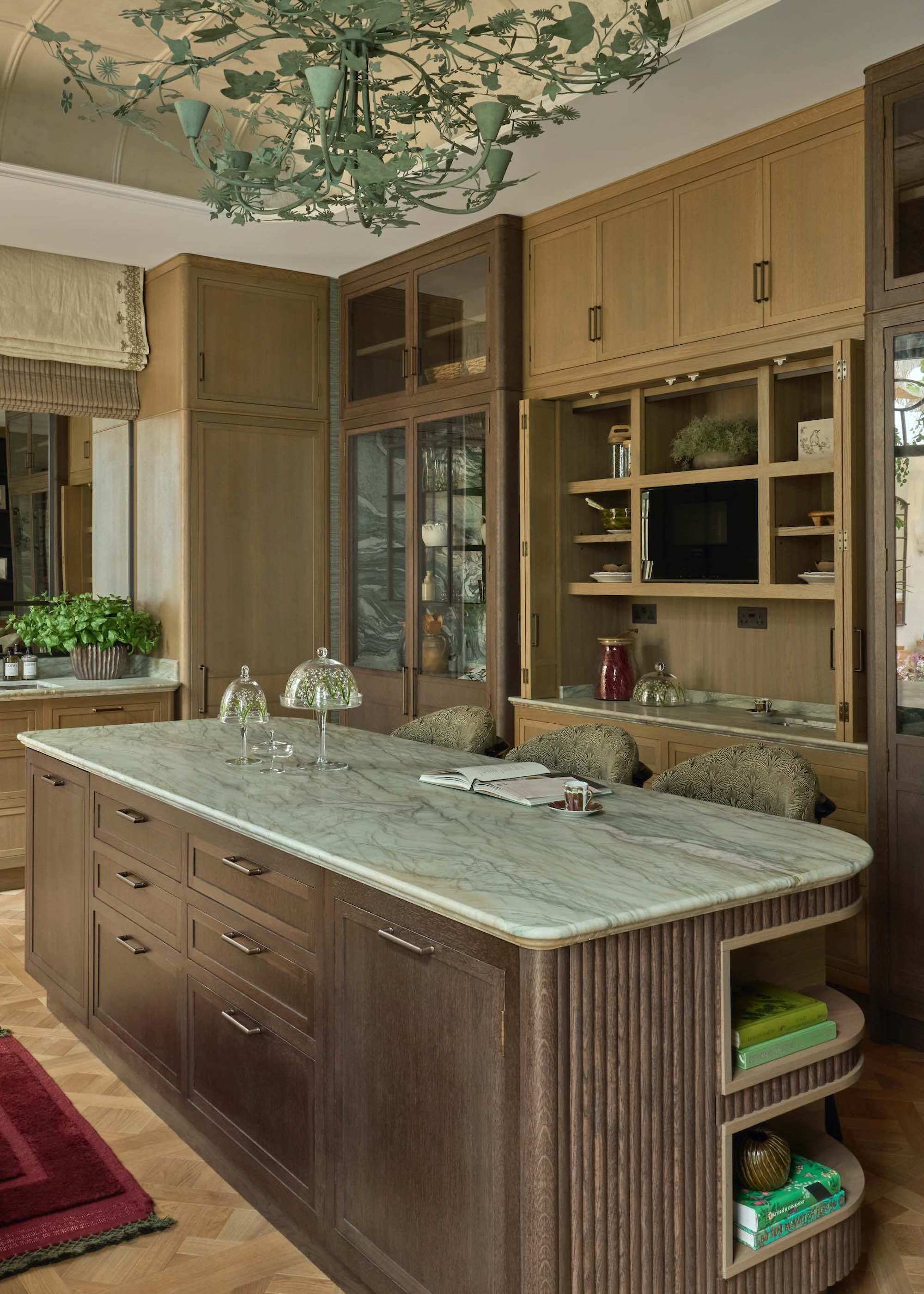 two tone timber kitchen with green marble tops , and a large decorative green chandelier from the ceiling.