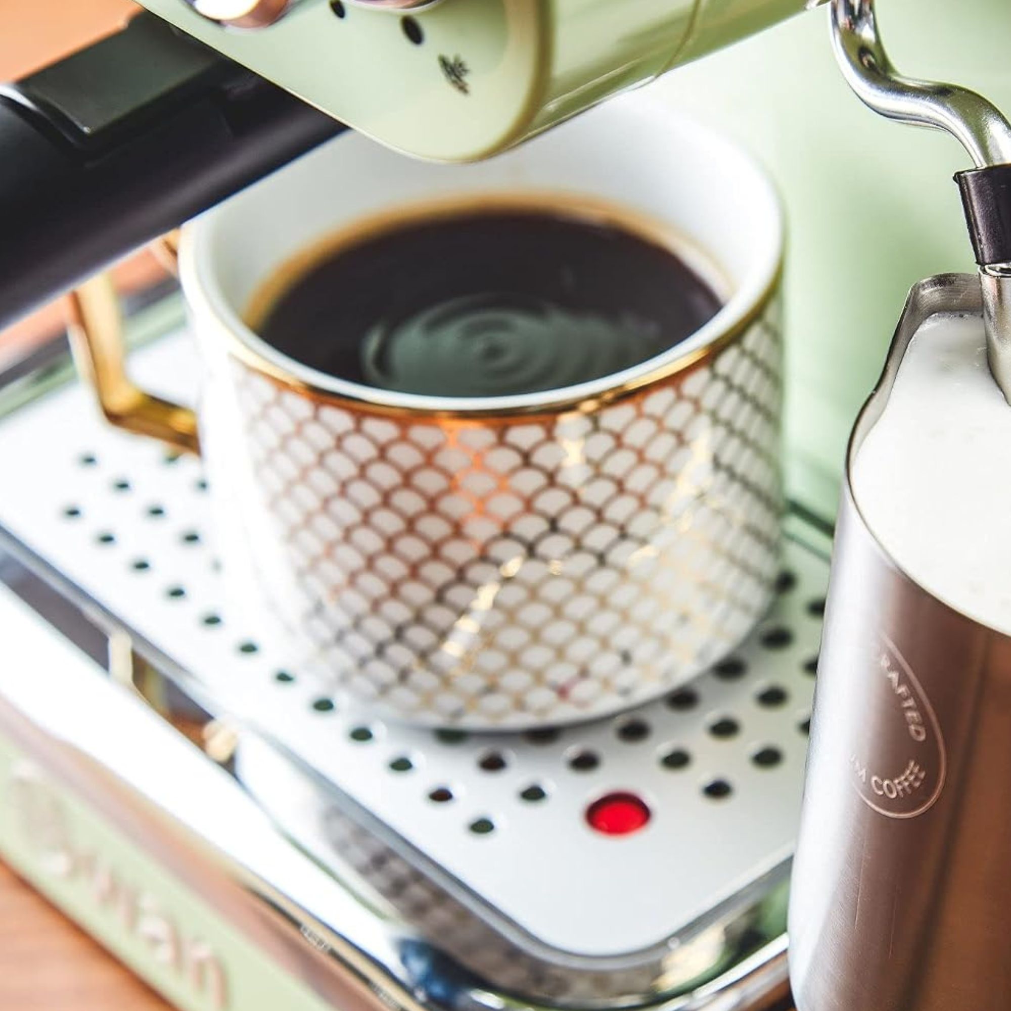 Green Swan coffee machine with coffee in mug on drip tray and milk in jug under frother