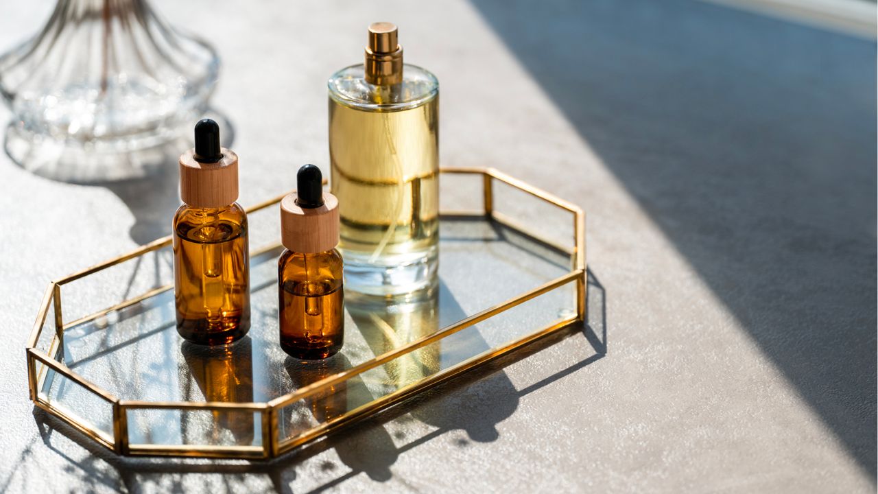 Bottles of perfumes and oils on mirrored tray 