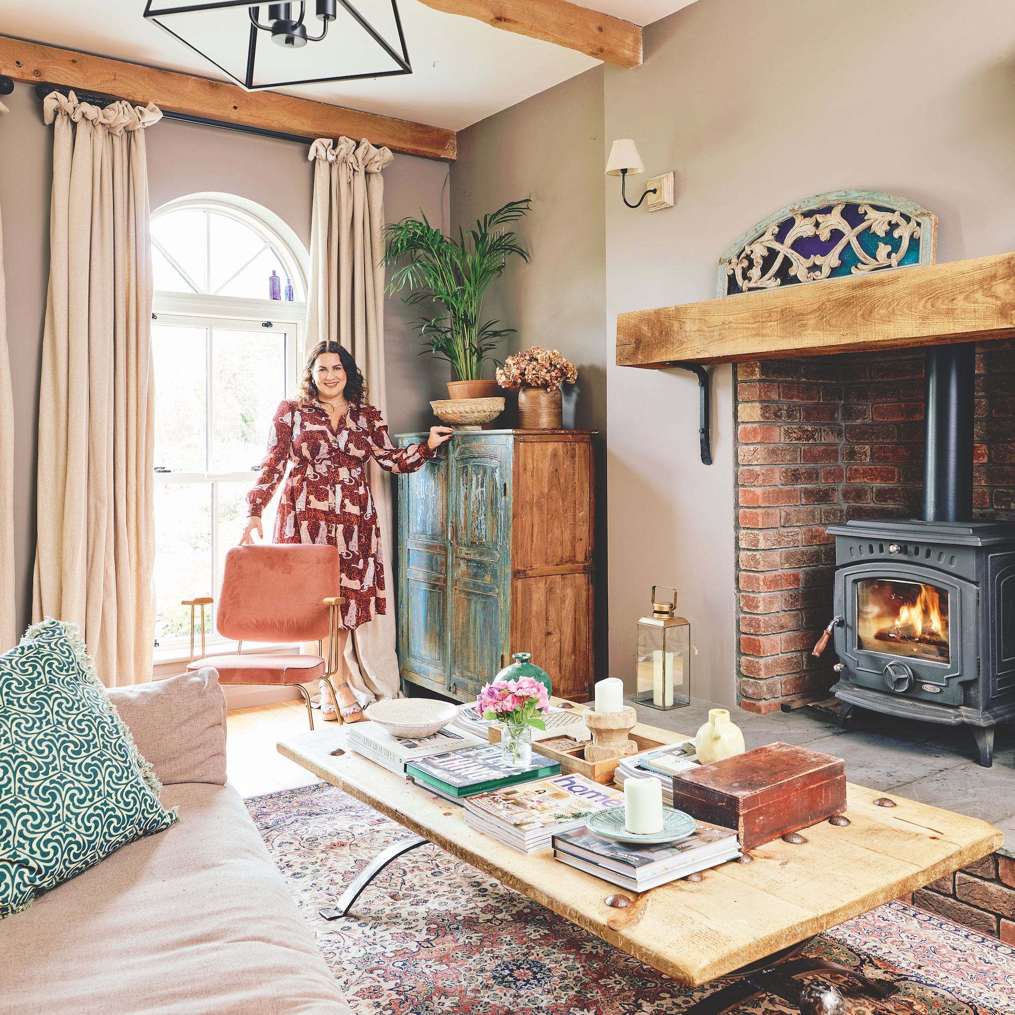 living room with beige walls wiht wooden coffee table and large brick fireplace with woodburning stove