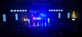 A house-of-worship stage alit in blue and purple lighting as a band plays.