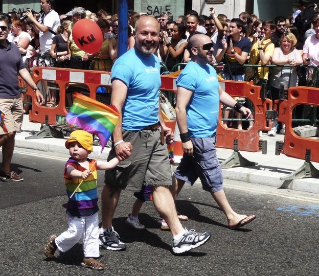 Gay parents march with their child in a Pride parade.