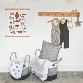 A Scandi-style kids' room with striped grey storage baskets and clothes hung on wooden hooks