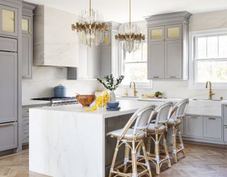 gray and white marble kitchen, marble kitchen island, bar stools, gray cabinetry and wall cabinets, modern lights, herringbone floor
