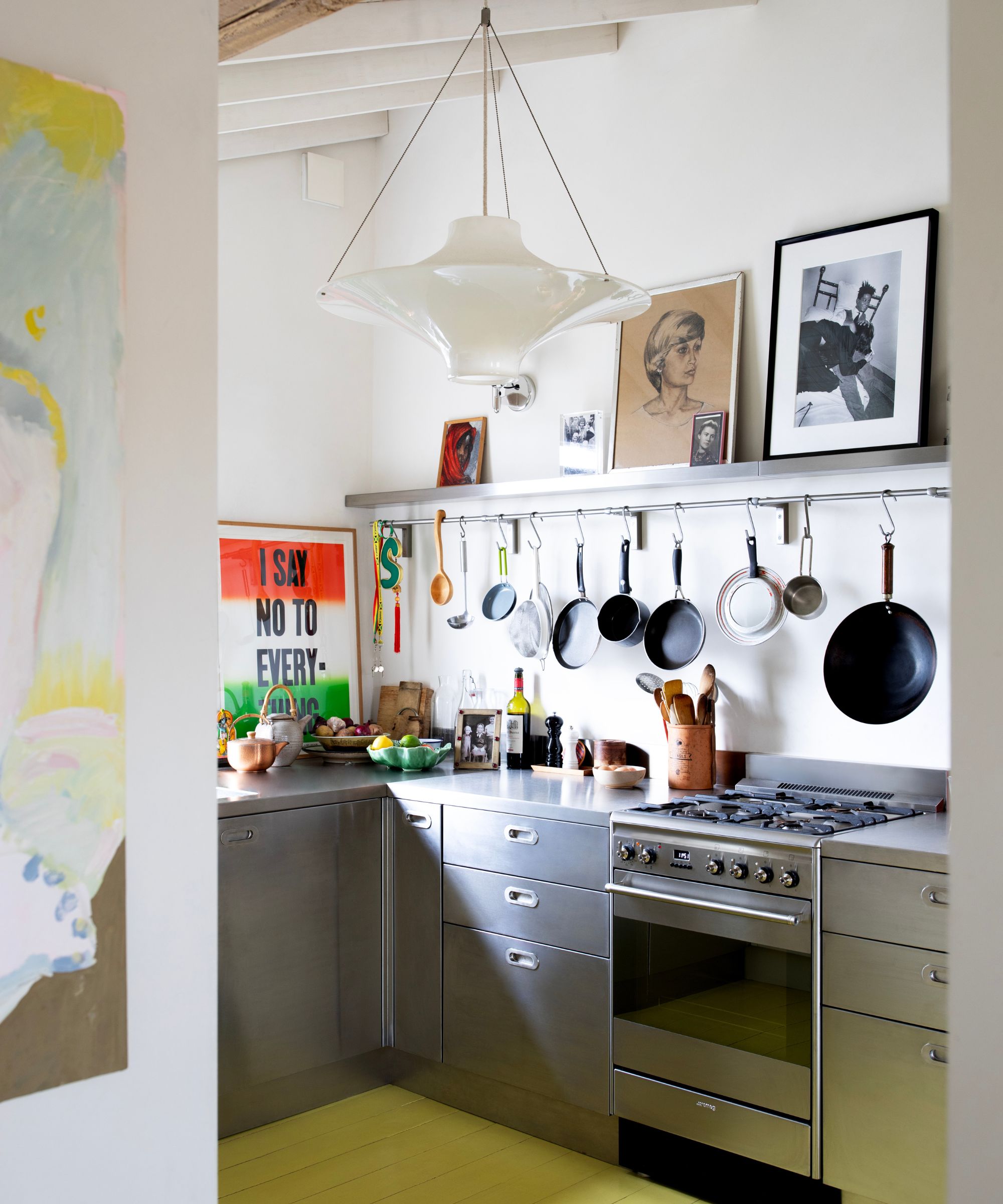 A small apartment kitchen with stainless steel cabinets, white walls, and lime green floors