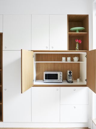 An all-white kitchen with a hidden storage for the microwave