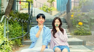 Jung Hae-in and Jung So-min, holding lollipops to their mouths while sitting on outdoor stairs, in the k-drama 'Love Next Door'