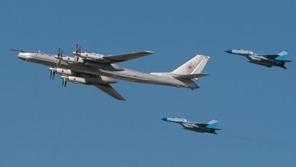 Russian startegic bomber TU-95 surrounded by MiG-29 flies over Monino airfield, some 40 km from Moscow, during an air show marking 95th anniversary of foundation of Russian Air Forces, 11 Aug