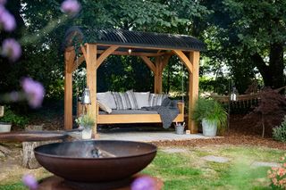 Swinging bench seat with canopy in a large garden