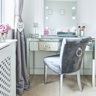 mirrored dressing table in grey bedroom with velvet chair