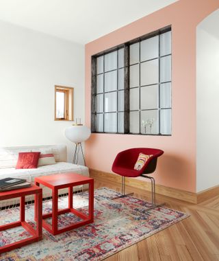 Living room with light pink wall and red accent furniture
