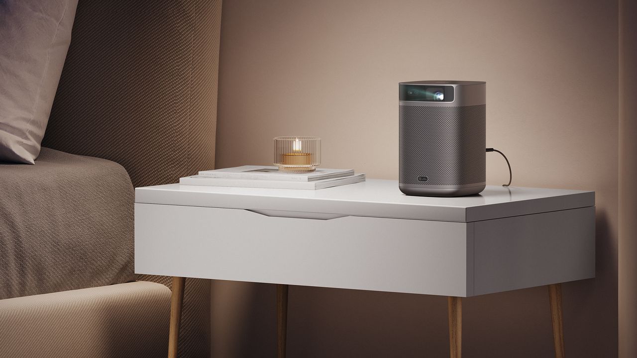 XGIMI MoGo 2 Pro on white side table next to lit tealight candle