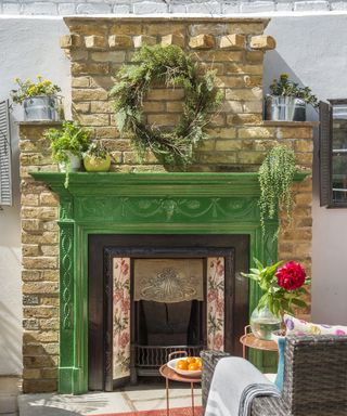 A green outdoor fireplace with mantle and wreath