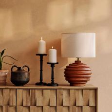 Beige room with wooden sideboard, wooden lamp and black candlestick holders