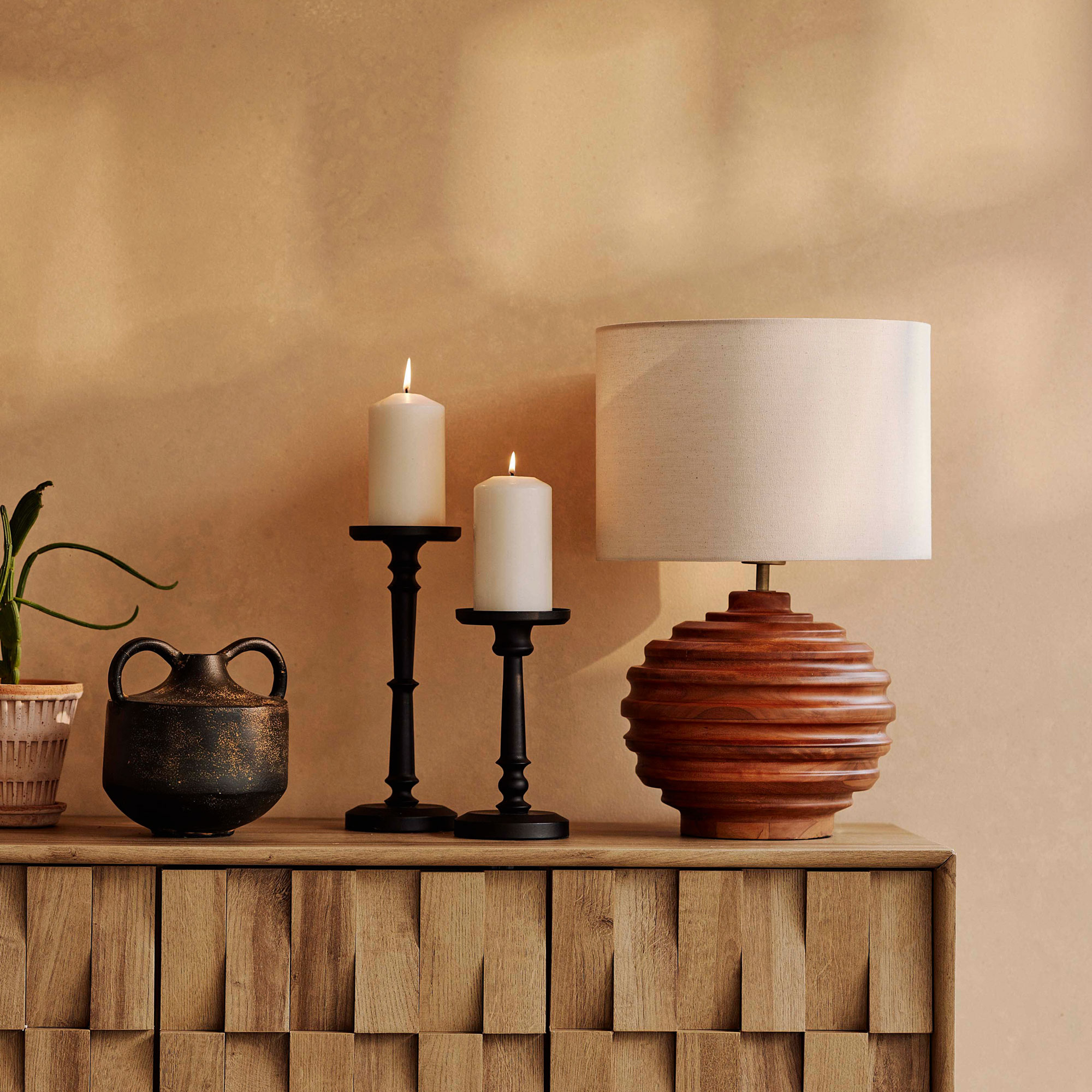 Beige room with wooden sideboard, wooden lamp and black candlestick holders