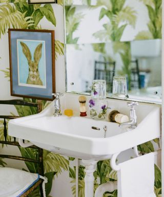 bathroom with large leafy wallpaper and a bunny rabbit art print
