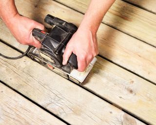 person sanding decking boards