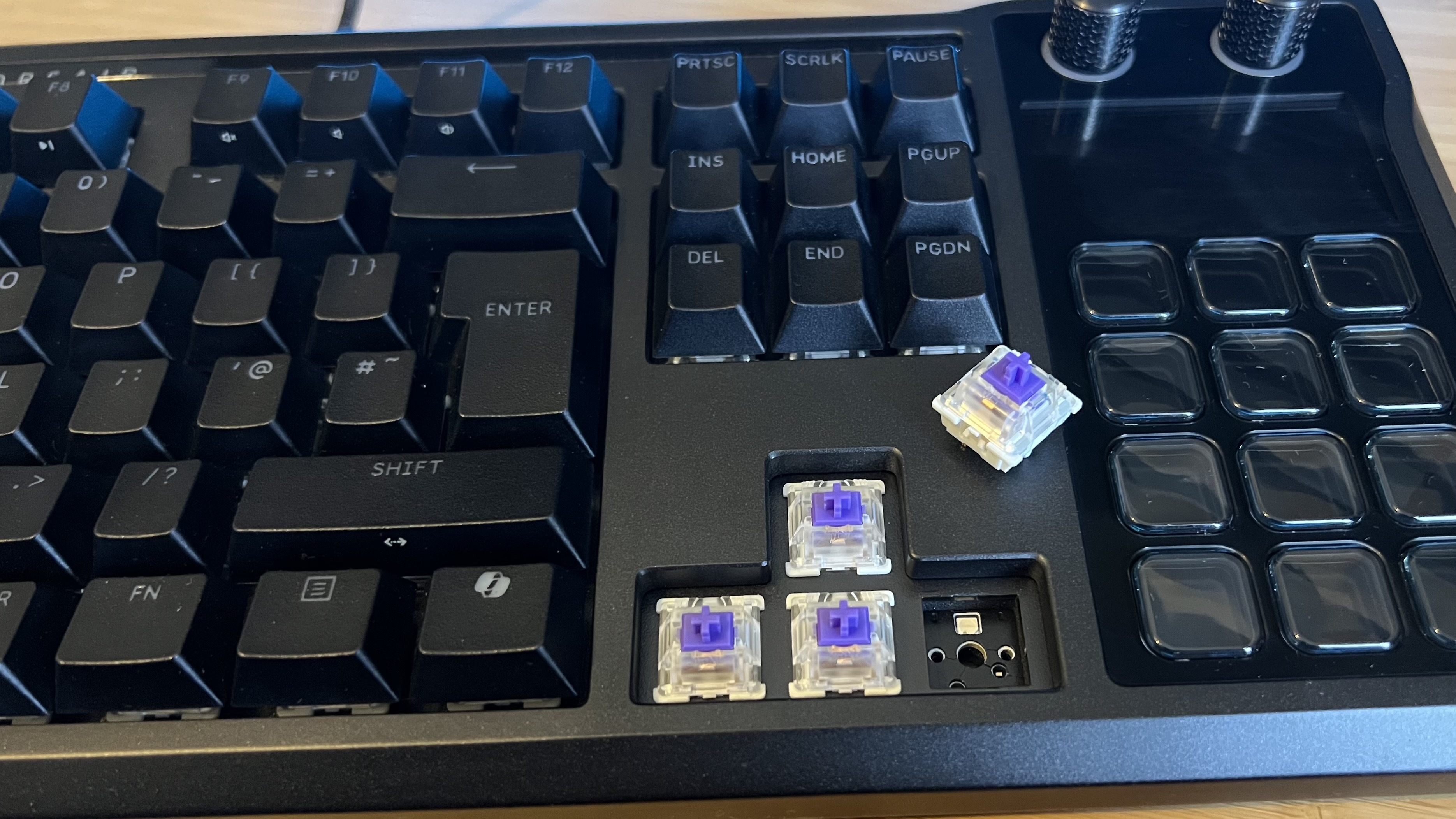 Close up on purple switches inside Corsair Galleon 100 SD gaming keyboard, with one switch removed to show PCB underneath