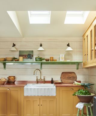 yellow kitchen units and sink beneath two skyiights