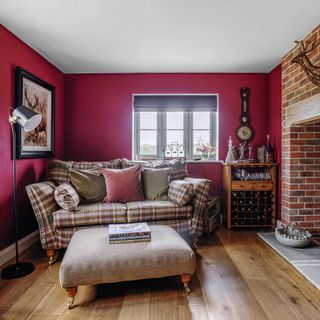 small living room with red walls, brick fireplace and compact two-seater sofa in a check fabric