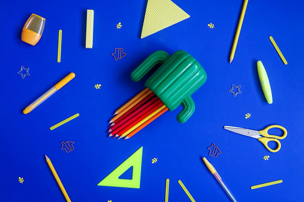 school supplies and a cactus pencil cup on a bright blue background