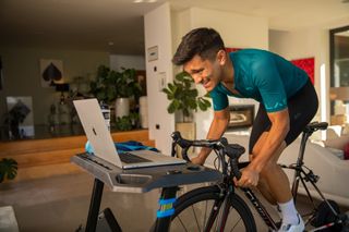 Image shows Sam riding indoors on a turbo trainer