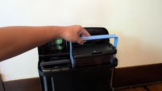 A hand lifting the water tank out of the Shark PowerDetect Robot Vacuum and Mop's charging station