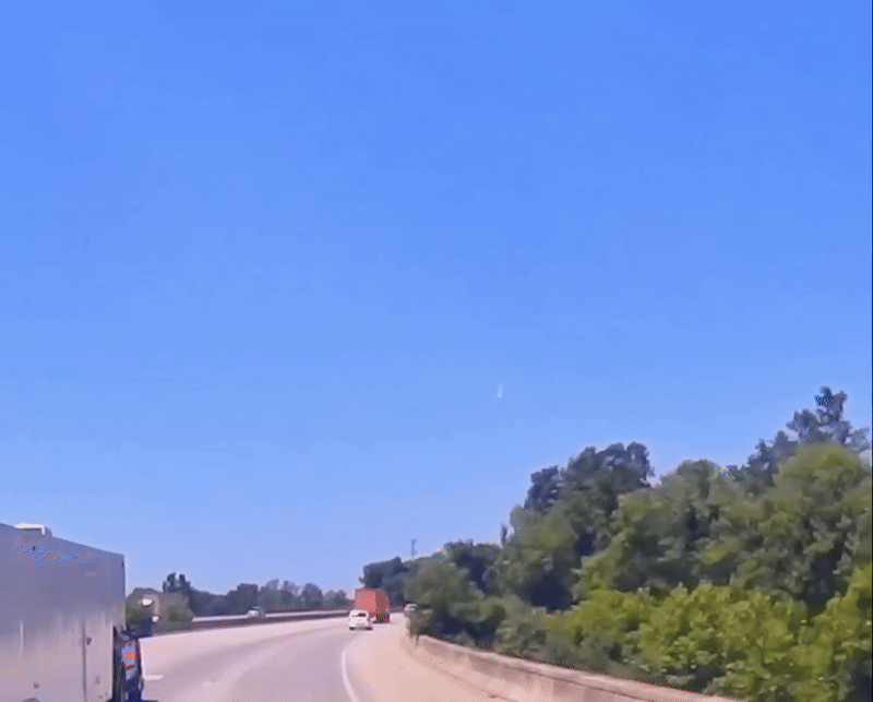 A fireball is captured streaking through a clear blue sky through a camera affixed to the windscreen of a vehicle
