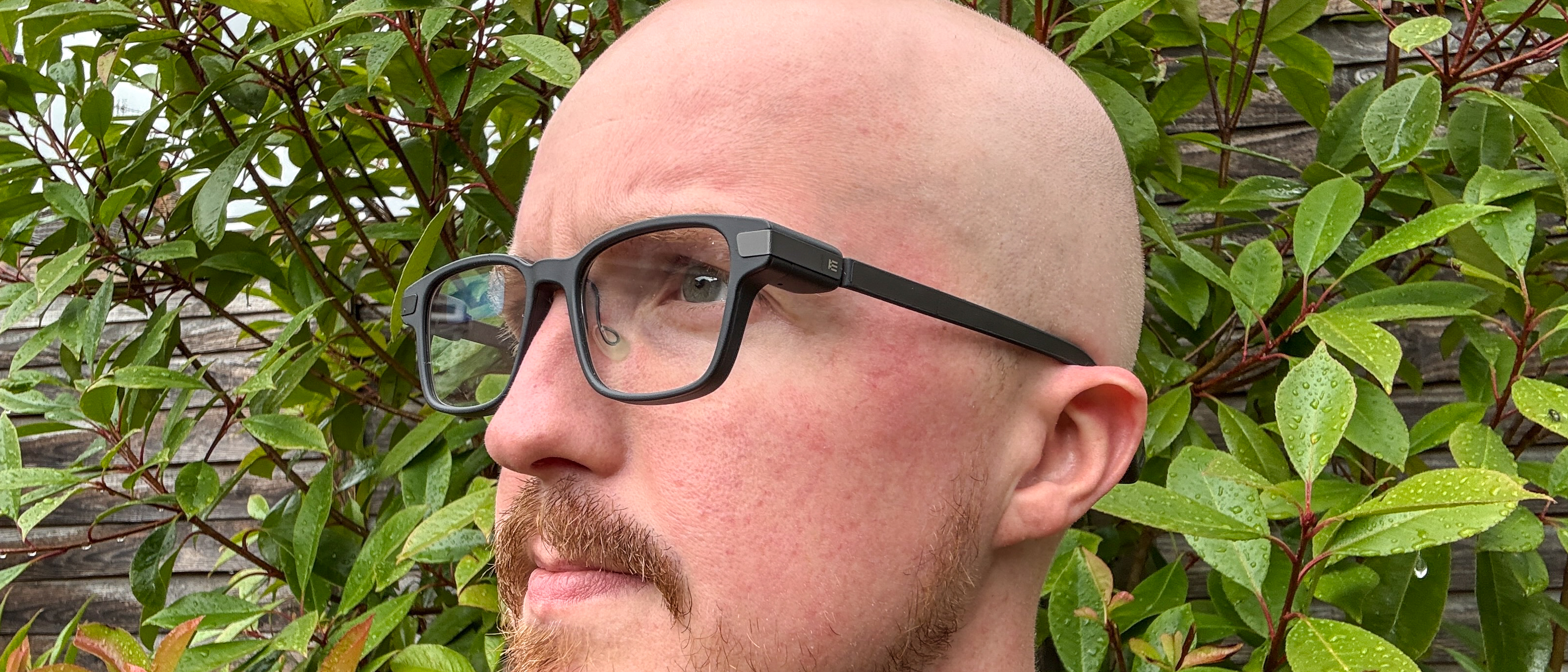 Even Realities G1 Smart Glasses being worn by person with bush and fence in background