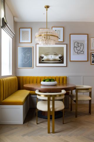 Dining room with beige walls, mustard banquette seating and gold and cream dining chairs