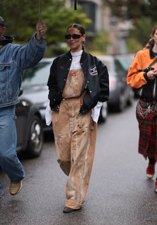 woman wearing overalls, a turtleneck, and a jacket