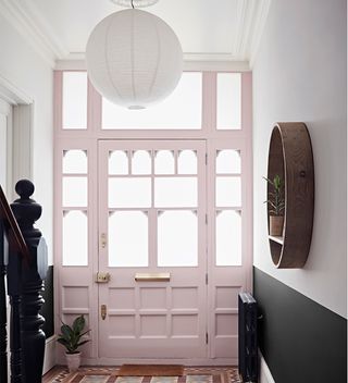 narrow hallway with pink front door and pendant light