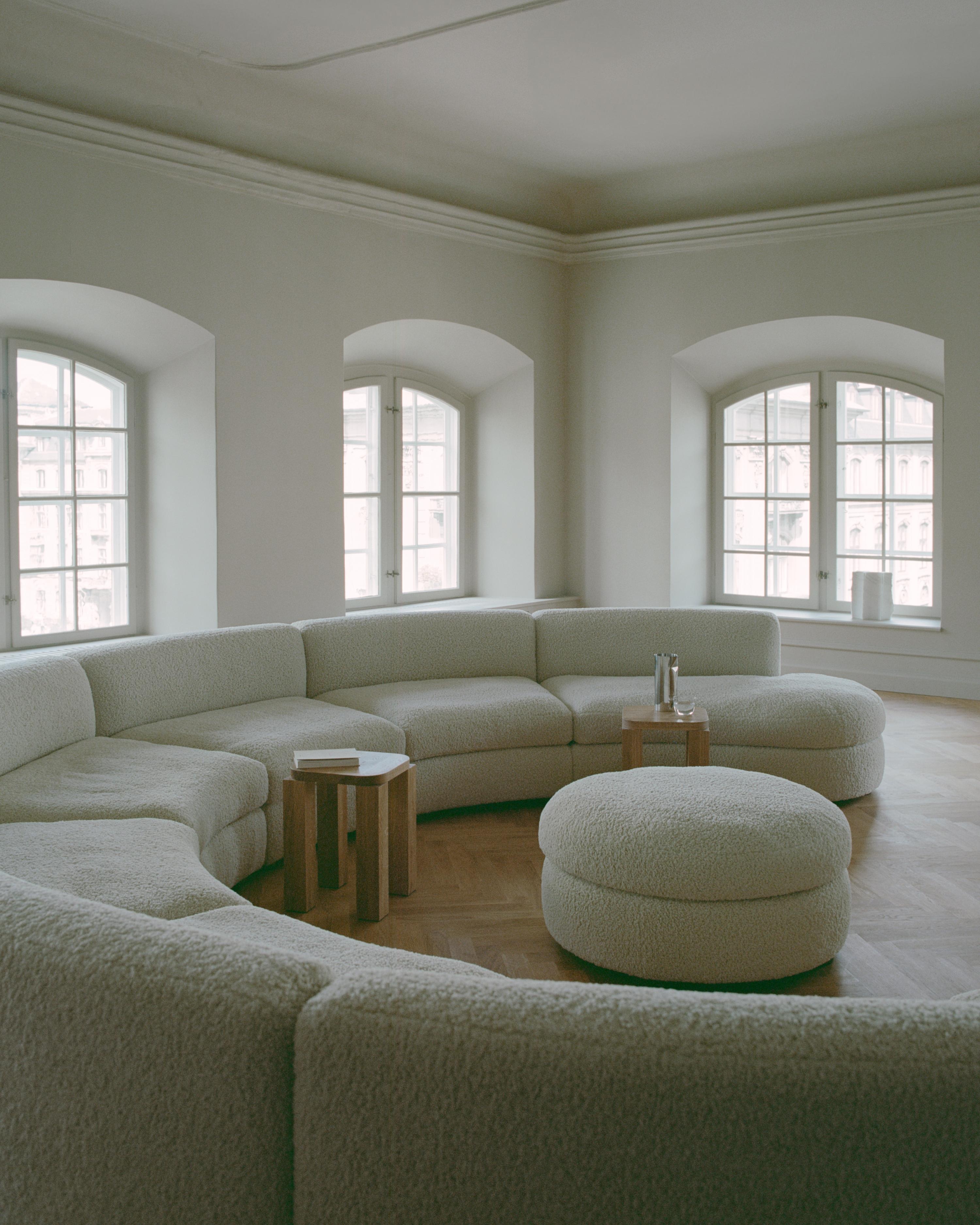 a scandi living room with neutral furniture and a curved round sofa