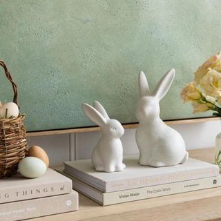 Two white porcelain bunnies sitting atop a stack of books.