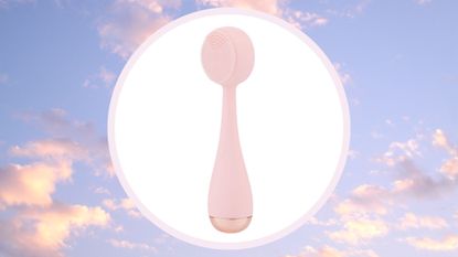 pale pink PMD Clean facial cleansing brush on a pastel pink and blue cloud background