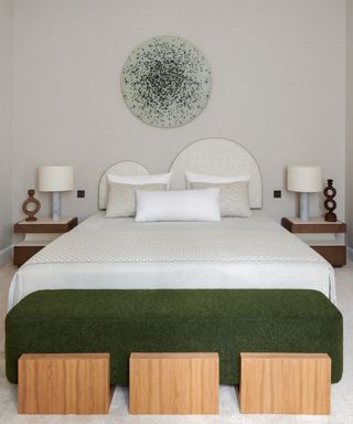 neutral bedroom with wavey headboard and green accessories