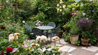 metal garden furniture surrounded by potted plants and flowers