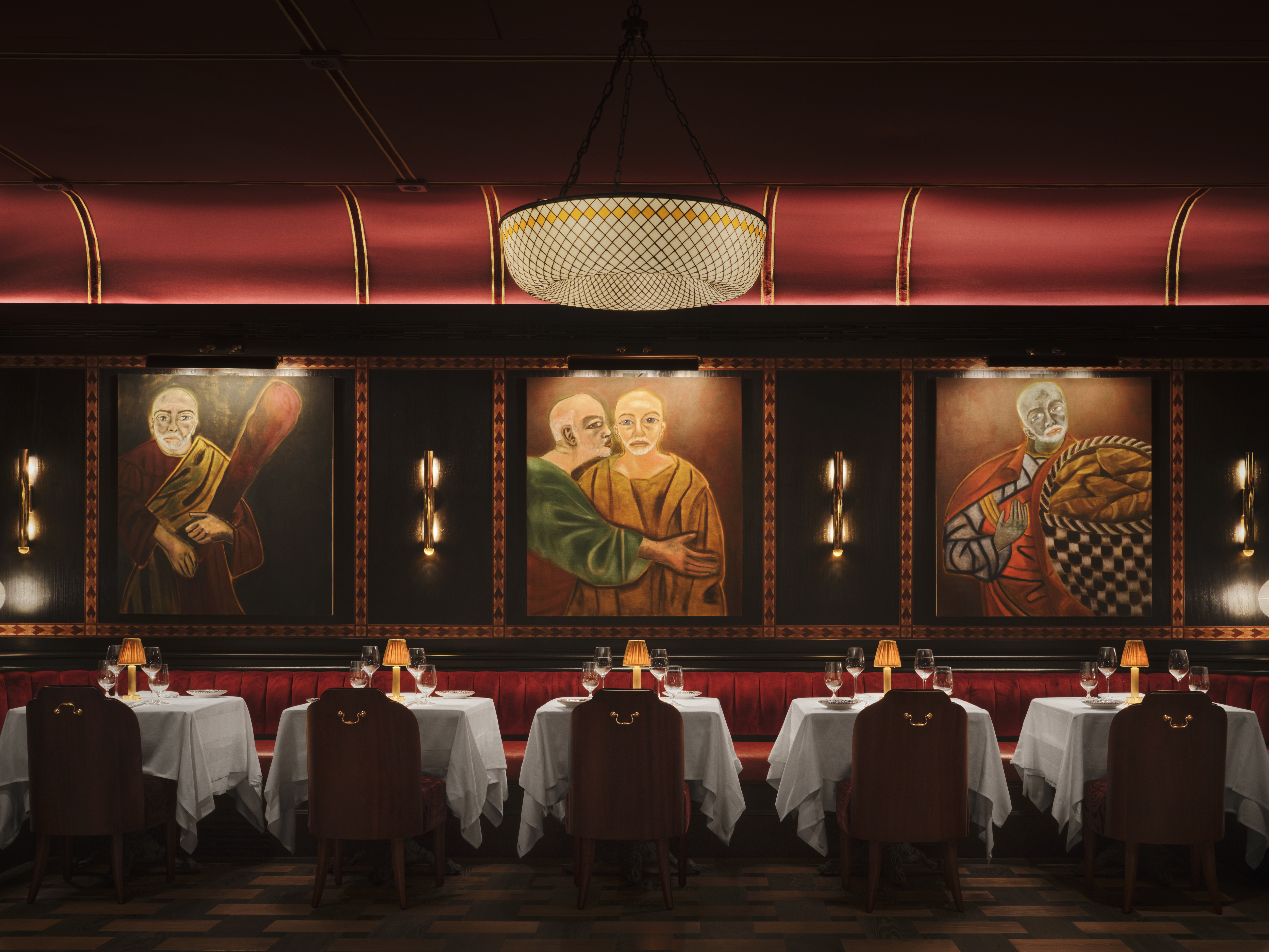 A dazzling decorated restaurant with checkered, red and white marble floors, red velvet drapery, banquettes, and leather chairs, ciambella-shaped lighting with a golden glow, and softly burning table lamps.