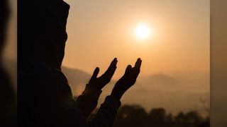 A person is silhouetted against the sun