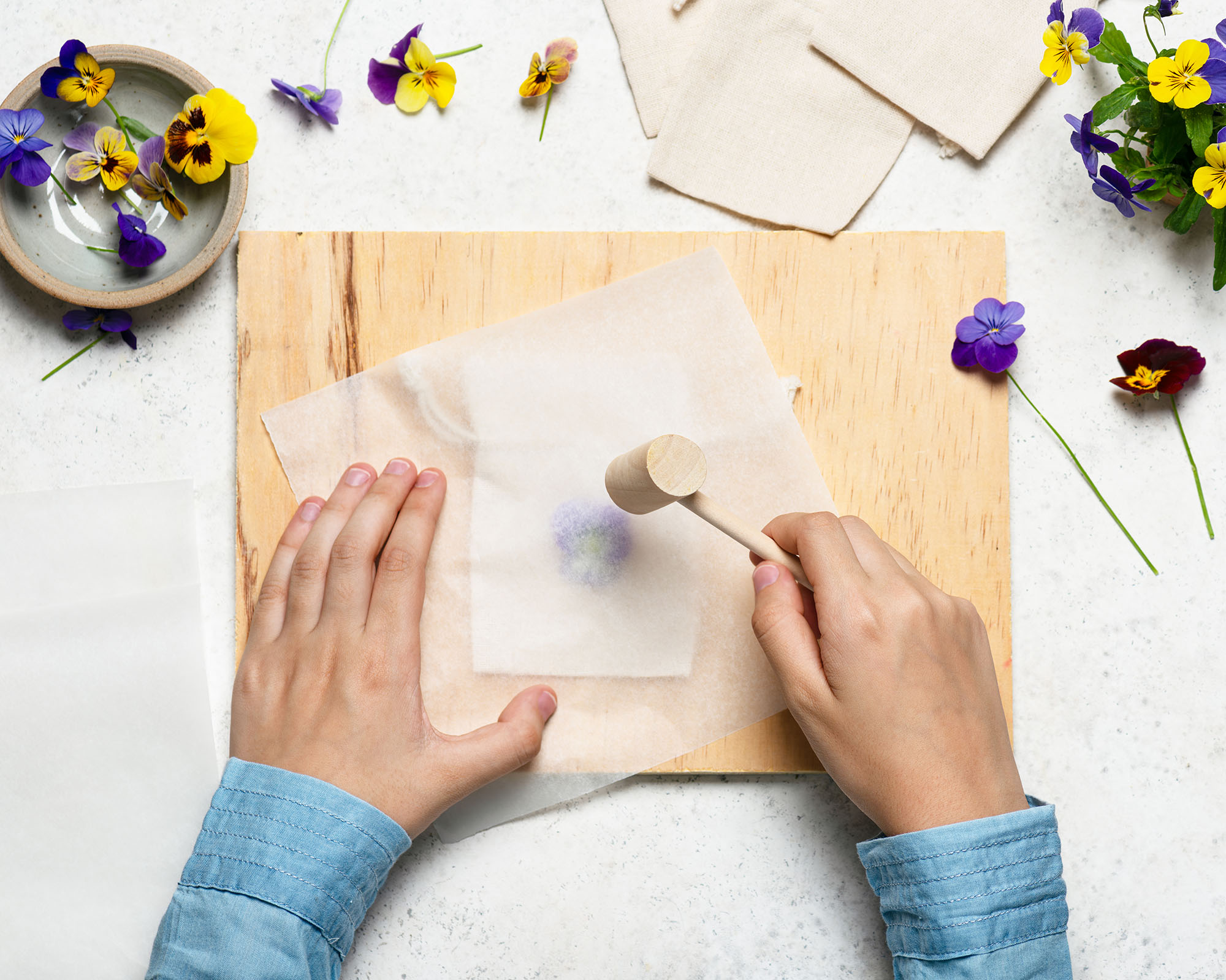 Crafter takes a hammer and begins to pound the flower to create nature printed fabric