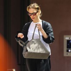 Jennifer Lawrence walks down the street in New York wearing black trousers with slides and a white t-shirt.